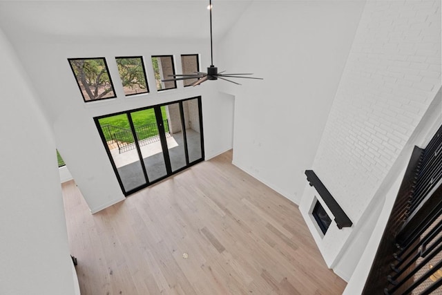 162 Leaning Rock Rdg, Austin, TX 78737 - unfurnished living room with a towering ceiling, light wood-type flooring, ceiling fan, and a fireplace