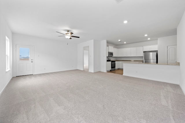 unfurnished living room with ceiling fan and light colored carpet