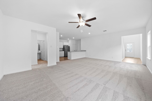 unfurnished living room featuring light carpet and ceiling fan