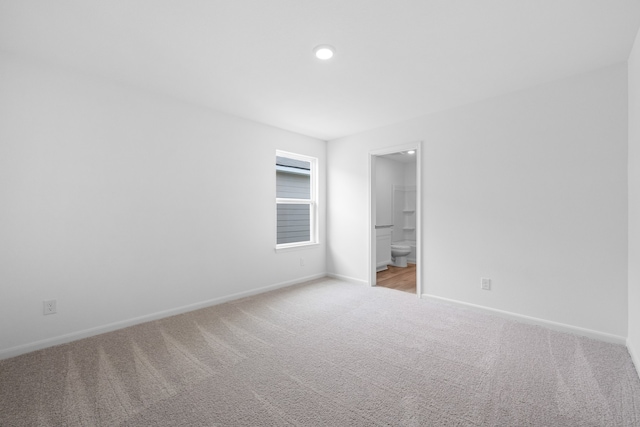 unfurnished bedroom featuring ensuite bath and light colored carpet