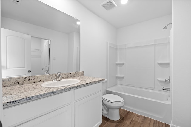 full bathroom with hardwood / wood-style floors, shower / tub combination, vanity, and toilet