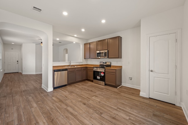 kitchen featuring ceiling fan, sink, light hardwood / wood-style flooring, and stainless steel appliances