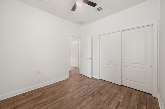 unfurnished bedroom featuring ceiling fan, a closet, and light wood-type flooring