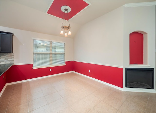 unfurnished dining area featuring tile patterned flooring, a chandelier, and vaulted ceiling