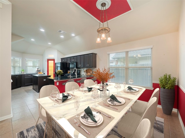 dining room featuring a healthy amount of sunlight, vaulted ceiling, a notable chandelier, and light tile patterned flooring