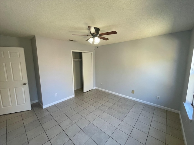 unfurnished bedroom with ceiling fan, light tile patterned floors, a closet, and a textured ceiling