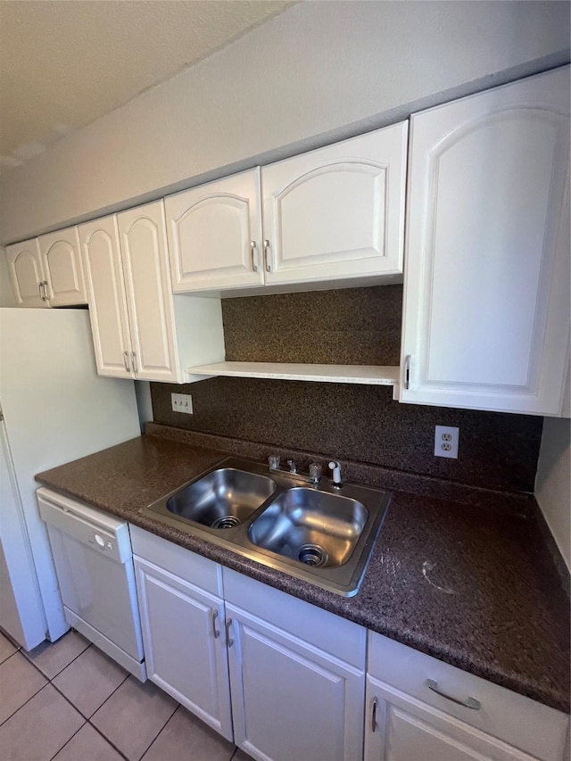 kitchen with light tile patterned floors, sink, white dishwasher, and white cabinetry