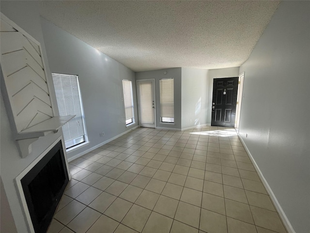 unfurnished living room with a textured ceiling and light tile patterned flooring