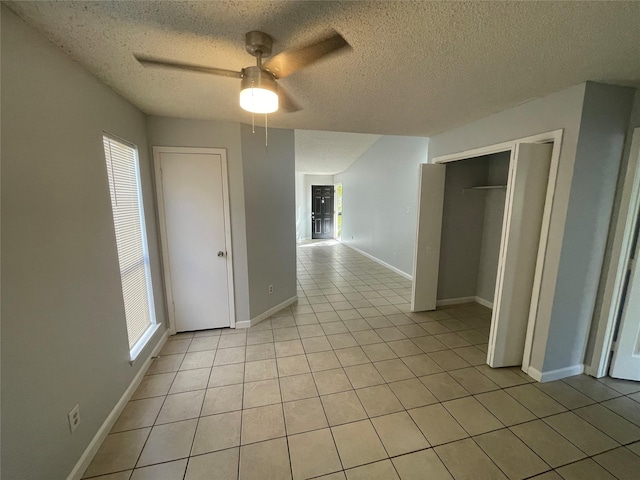 hall featuring a textured ceiling, light tile patterned floors, and a wealth of natural light