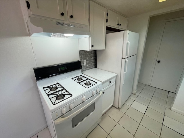 kitchen with light tile patterned floors, decorative backsplash, white appliances, and white cabinetry