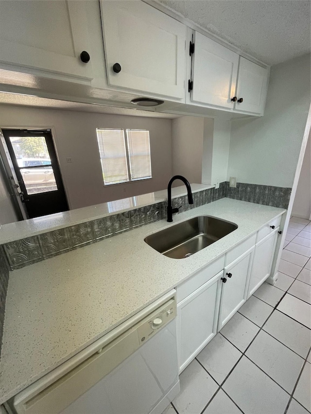 kitchen with white cabinets, sink, kitchen peninsula, light tile patterned flooring, and white dishwasher