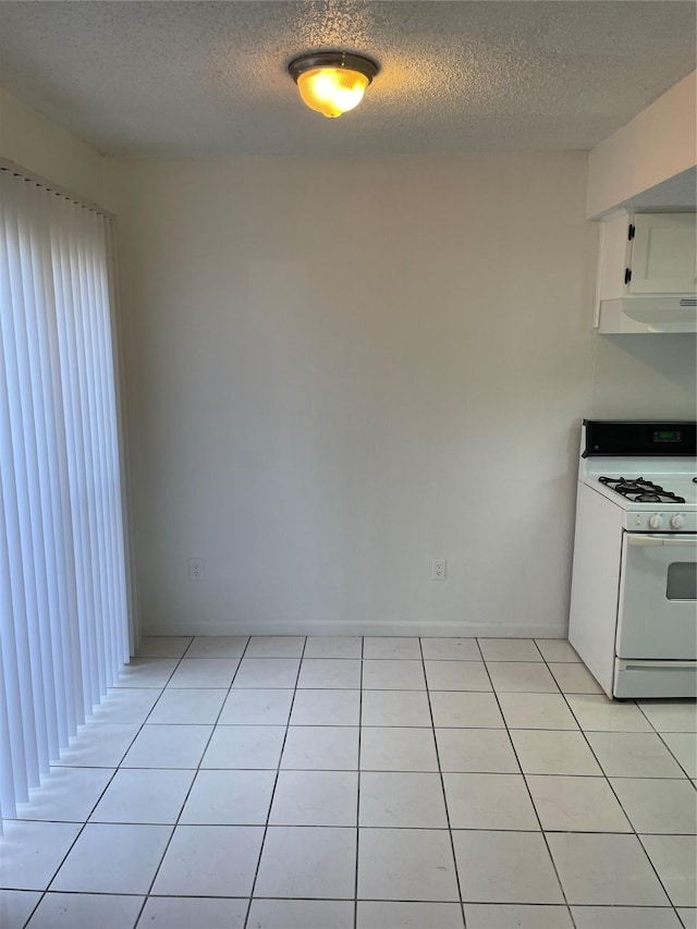 kitchen with light tile patterned floors, white gas stove, white cabinetry, and a textured ceiling