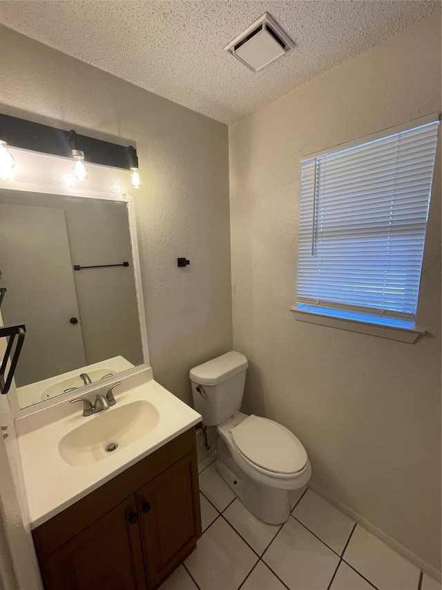 bathroom with a textured ceiling, toilet, vanity, and tile patterned flooring