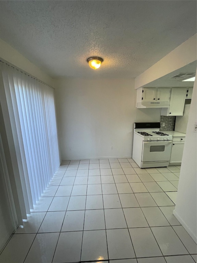 kitchen featuring tasteful backsplash, light tile patterned floors, white cabinetry, and white range with gas cooktop