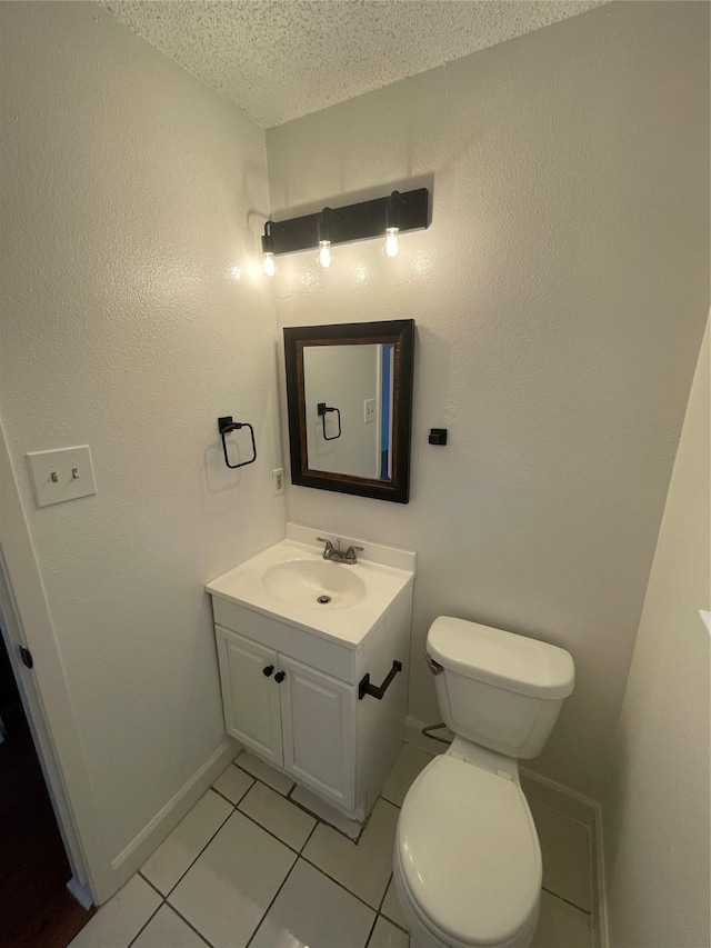 bathroom featuring toilet, vanity, tile patterned flooring, and a textured ceiling