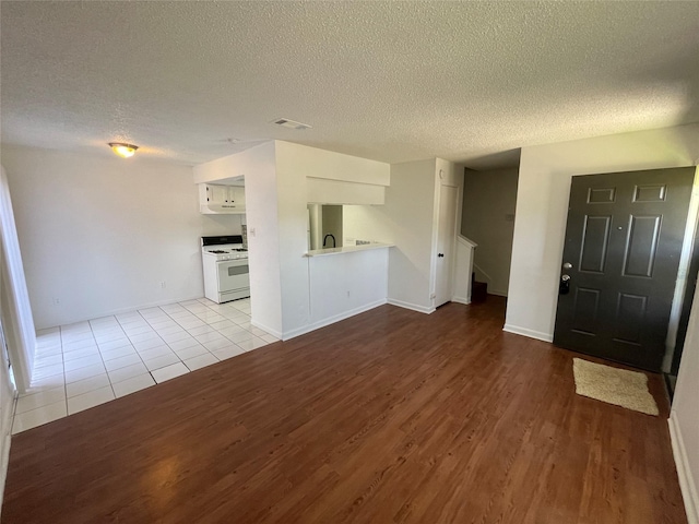 unfurnished living room with a textured ceiling and light wood-type flooring