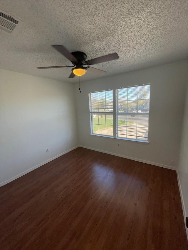 empty room with a textured ceiling, dark wood-type flooring, and ceiling fan