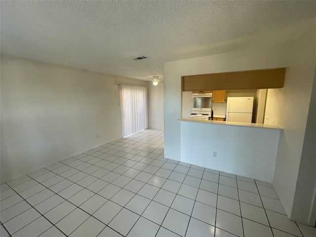 empty room with ceiling fan, light tile patterned floors, and a textured ceiling