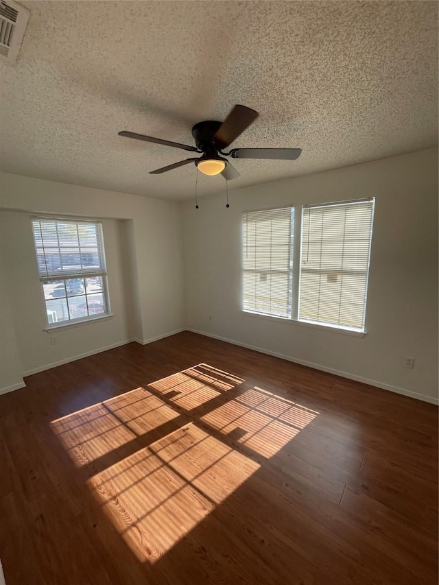 spare room with a textured ceiling, dark wood-type flooring, and ceiling fan