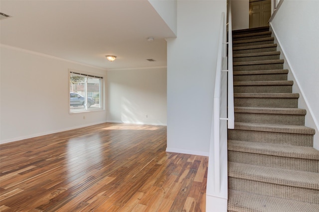 stairway featuring crown molding and hardwood / wood-style flooring