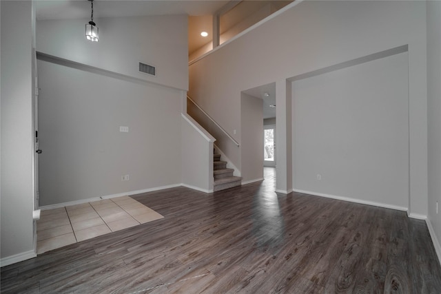 unfurnished living room with a high ceiling and dark hardwood / wood-style flooring