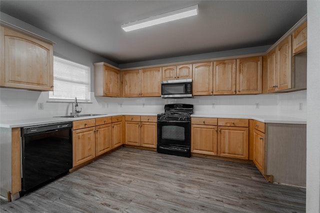 kitchen featuring black appliances, sink, light brown cabinets, and light hardwood / wood-style flooring