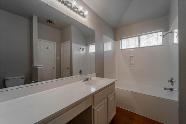 full bathroom featuring toilet, vanity, lofted ceiling,  shower combination, and hardwood / wood-style flooring