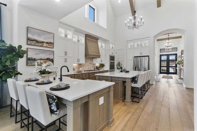 kitchen with stainless steel appliances, a large island with sink, white cabinetry, and a breakfast bar