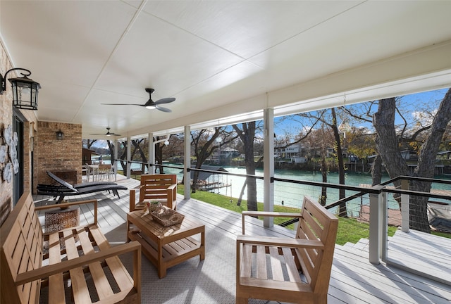 sunroom with ceiling fan and a water view