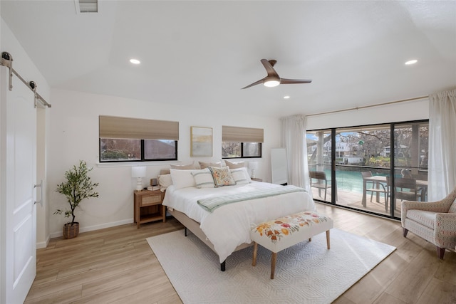 bedroom featuring ceiling fan, access to exterior, light hardwood / wood-style flooring, and a barn door