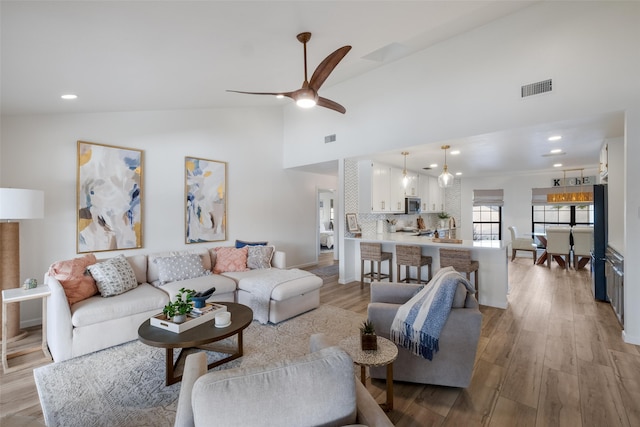 living room featuring ceiling fan, light hardwood / wood-style floors, and high vaulted ceiling