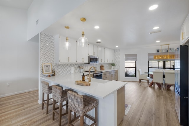 150 Turtle Ln, Seguin, TX 78155 - kitchen with appliances with stainless steel finishes, light countertops, light wood-type flooring, tasteful backsplash, and white cabinetry