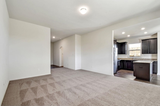 unfurnished living room featuring light carpet and sink