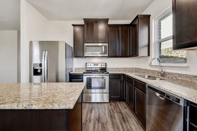 kitchen featuring light stone countertops, sink, appliances with stainless steel finishes, and light hardwood / wood-style floors