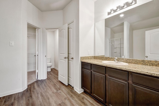 bathroom with toilet, vanity, wood-type flooring, and walk in shower