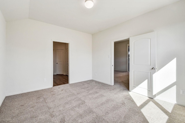 carpeted empty room featuring vaulted ceiling