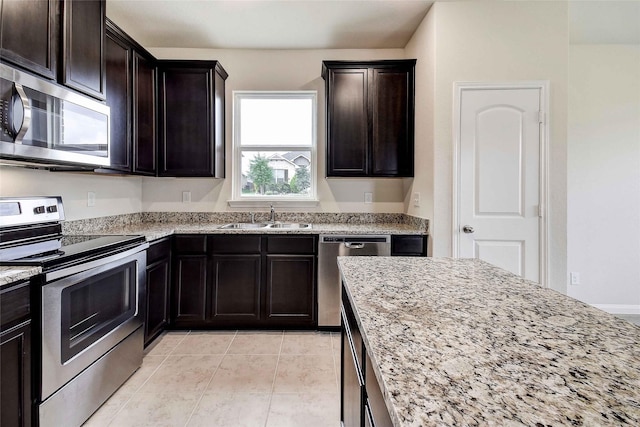 kitchen with light stone countertops, sink, stainless steel appliances, and dark brown cabinets