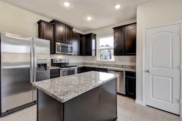 kitchen featuring a kitchen island, stainless steel appliances, light tile patterned flooring, light stone counters, and dark brown cabinets