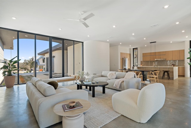 living room featuring ceiling fan and expansive windows