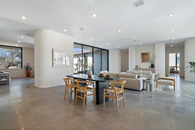 dining room featuring a wealth of natural light, floor to ceiling windows, and concrete flooring