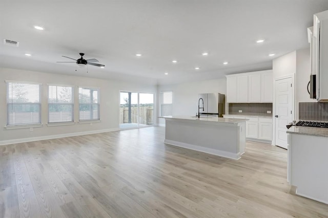 kitchen with white cabinetry, a center island with sink, and light hardwood / wood-style flooring