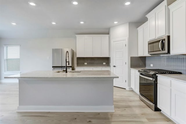 kitchen featuring appliances with stainless steel finishes, white cabinetry, and a center island with sink