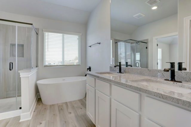 bathroom with hardwood / wood-style floors, vanity, separate shower and tub, and vaulted ceiling