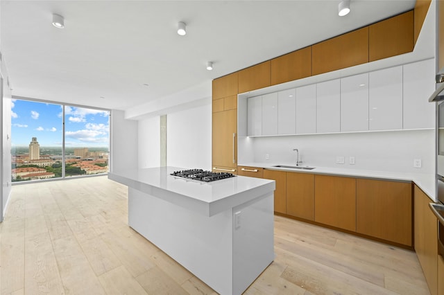 kitchen featuring a center island, light hardwood / wood-style floors, sink, expansive windows, and stainless steel gas cooktop