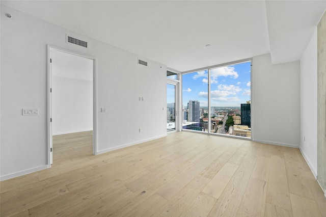 spare room featuring a wall of windows and light hardwood / wood-style flooring