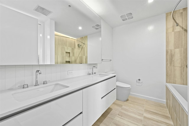 full bathroom featuring toilet, vanity, backsplash, tile patterned floors, and tiled shower / bath combo