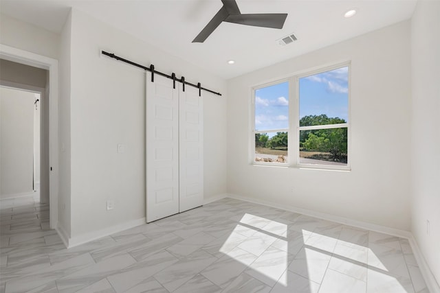 unfurnished bedroom featuring ceiling fan, a closet, and a barn door