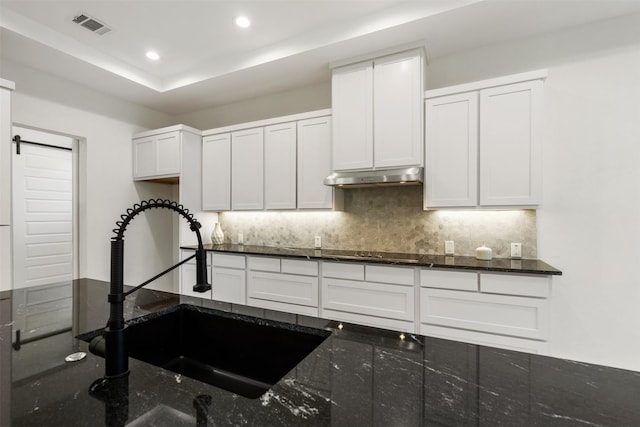 kitchen with white cabinets, tasteful backsplash, dark stone countertops, sink, and black electric cooktop