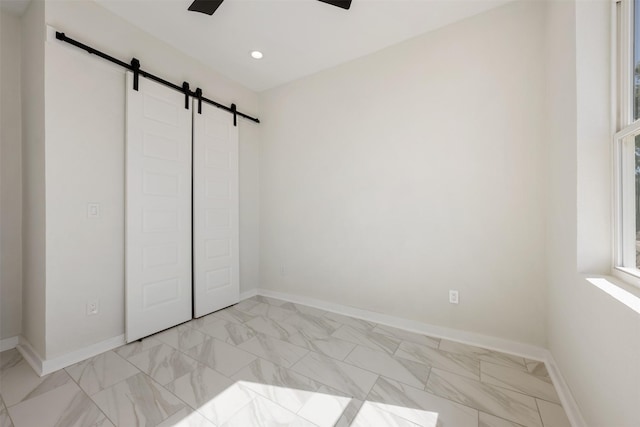 unfurnished bedroom featuring ceiling fan, a closet, and a barn door