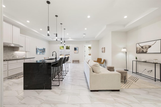 living room with sink and a raised ceiling